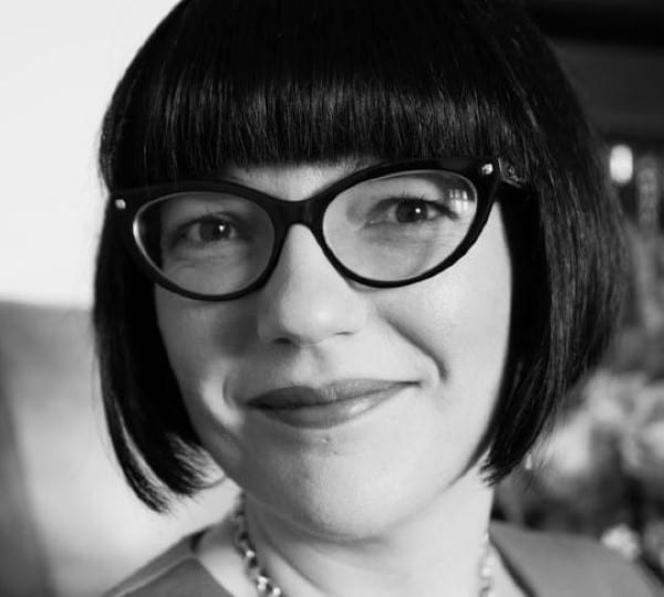 image of a woman with a fringe and glasses smiling into camera